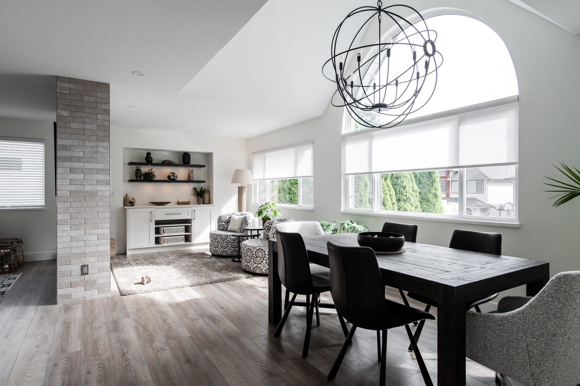 Bright open-plan dining and living area with vaulted ceiling, arched window and white built-in cabinetry