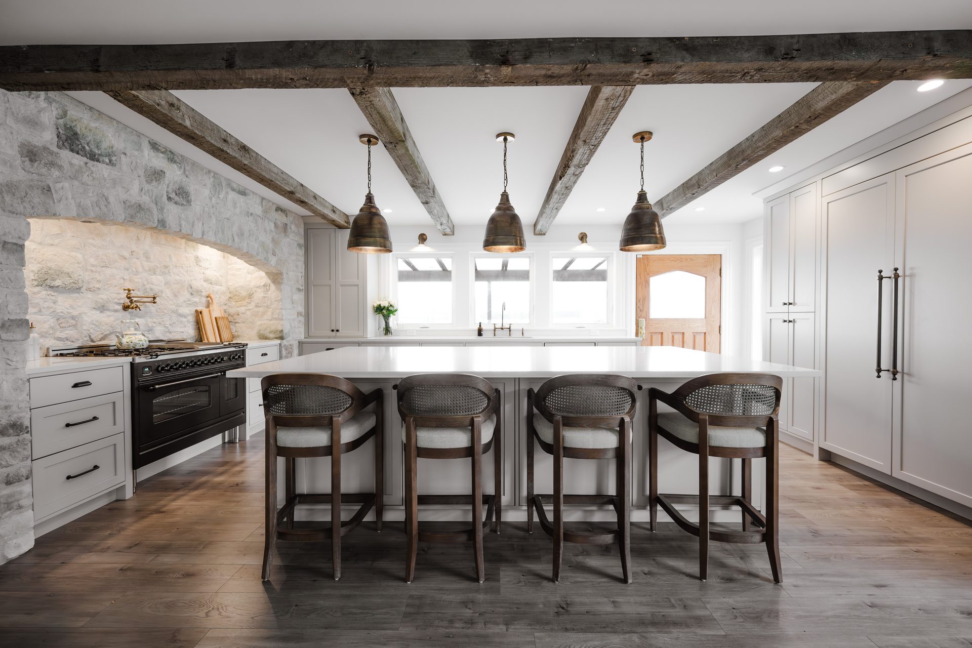 Bright kitchen renovation with white cabinetry, large island, ceiling beams and pendant lights